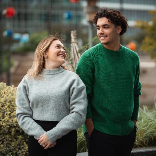 Etudiants de l'ESGCI, une fille blonde en pull gris regarde un homme avec un pull vert qui sourit dehort